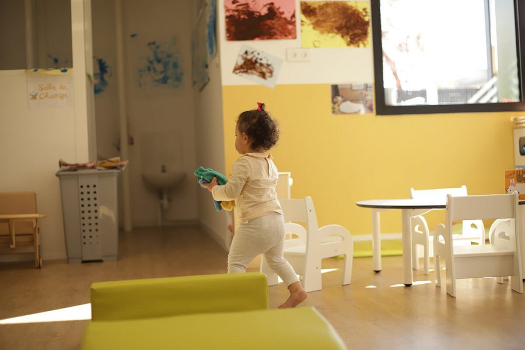 Un enfant marche en tenant des chiffons dans les mains, développant sa motricité et son équilibre.